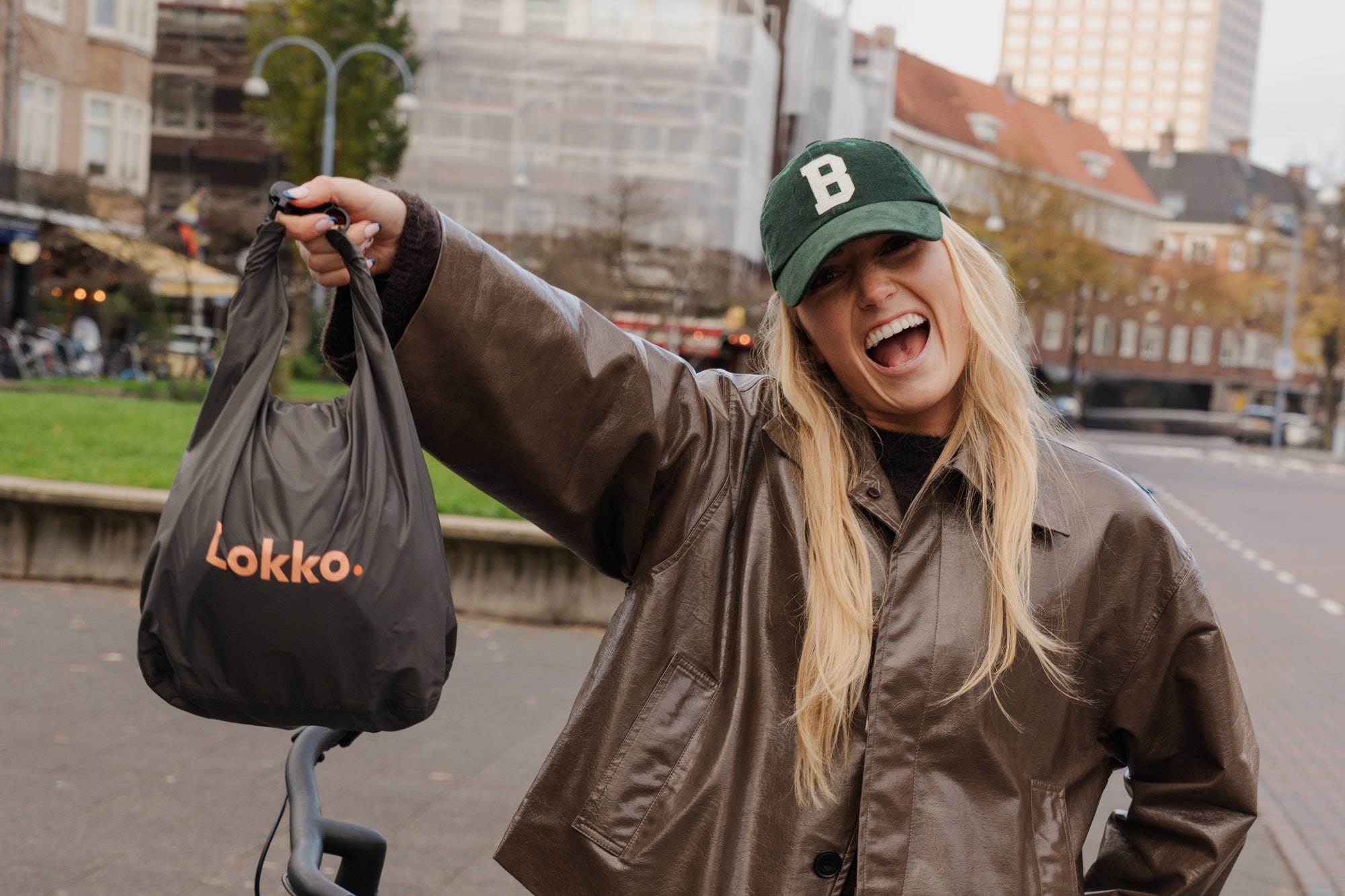 Happy Lokko customer holding her black helmet bag while out cycling in the city