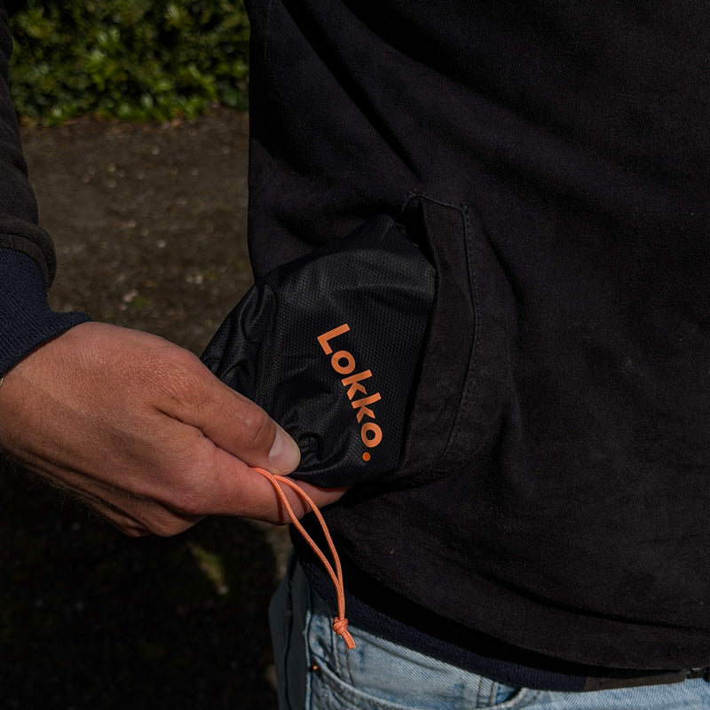 Person pulling the compact Lokko helmet bag out of a jacket pocket